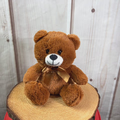 A brown bear that is 10 inches tall while sitting wearing a matching bow