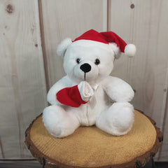 Medium sized white bear wearing a red Santa hat and holding a red stocking