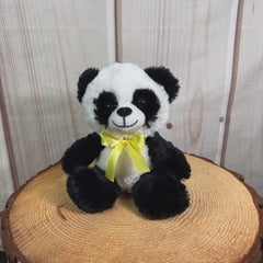 A black and white panda that is 7 inches tall while sitting wearing a yellow bow