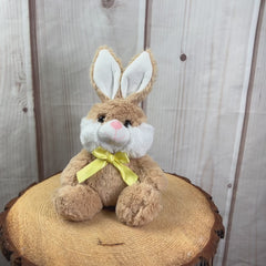 A beige rabbit that is 7 inches while sitting wearing a yellow bow