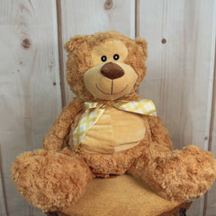 Beige stuffed bear wearing a yellow plaid bow