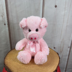 A light pink pig that is 7 inches tall while sitting wearing a matching bow