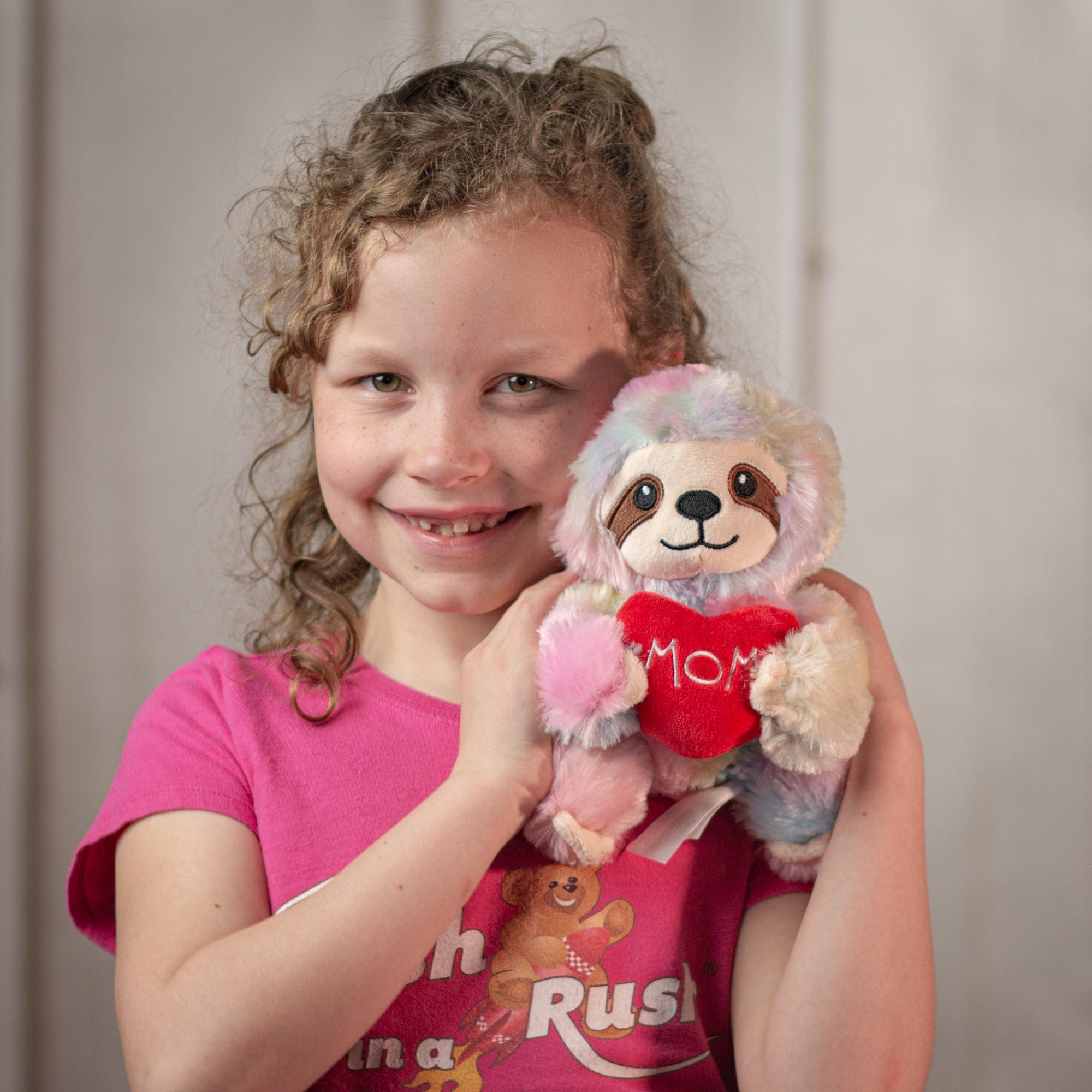 girl holding 6" Sloth Mom Duo one rainbow holding a heart that says mom