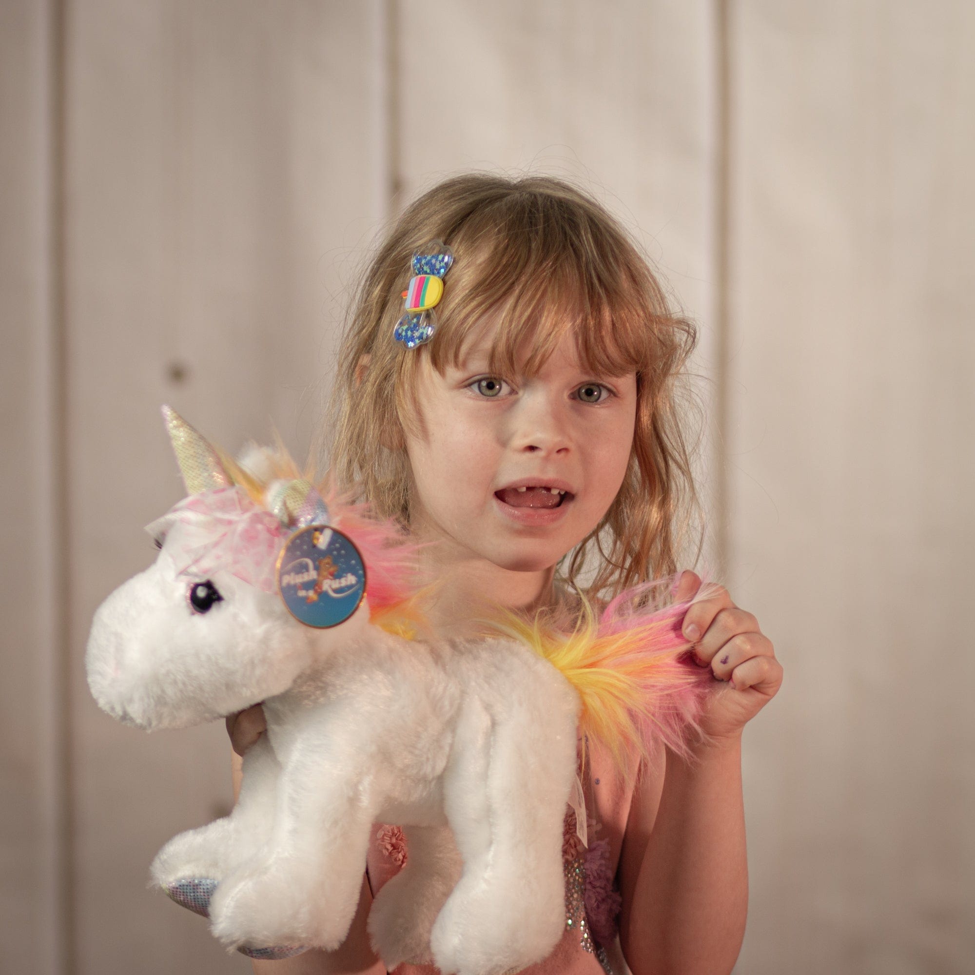 little girl holding 10" White Bella Unicorn with a rainbow main and horn with eyelashes