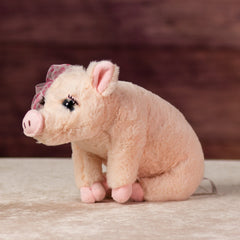 12 in stuffed pink pig wearing a bow and has eyelashes