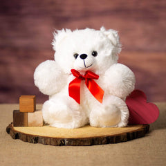 A white bear that is 11 inches tall while standing sitting on a piece of wood