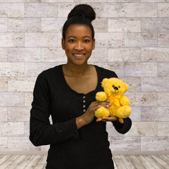 A woman holds a yellow bear that is 6 inches tall while sitting