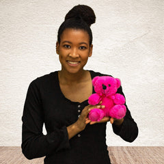 A woman holds a pink bear that is 6 inches tall while sitting