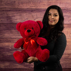 A woman holds a red bear that is 14 inches tall while sitting wearing a matching bow