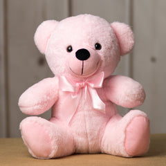 A light pink bear that is 14 inches tall while sitting wearing a matching bow