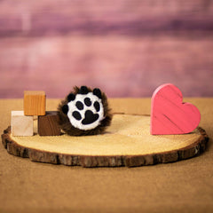 A black paw print that is 4 inches tall from top to bottom on top of a piece of wood