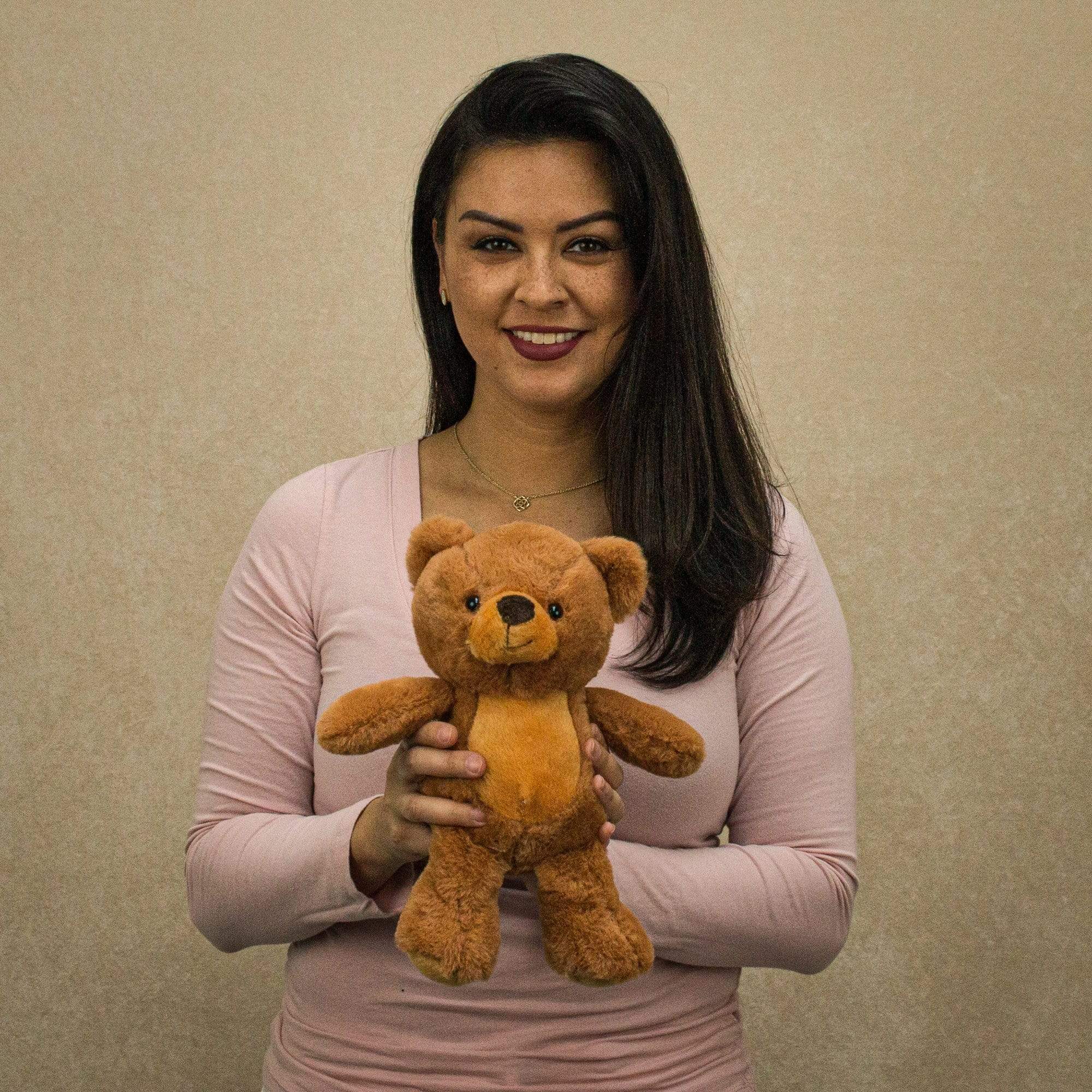 A woman holds a brown bear that is 11 inches tall while standing