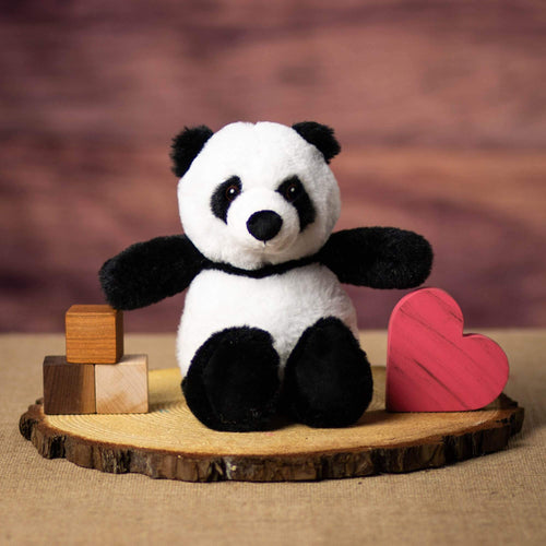 A black and white panda that is 11 inches tall while standing on a piece of wood