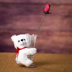 A white bear that is 5.5 inches tall while sitting hugging a vase