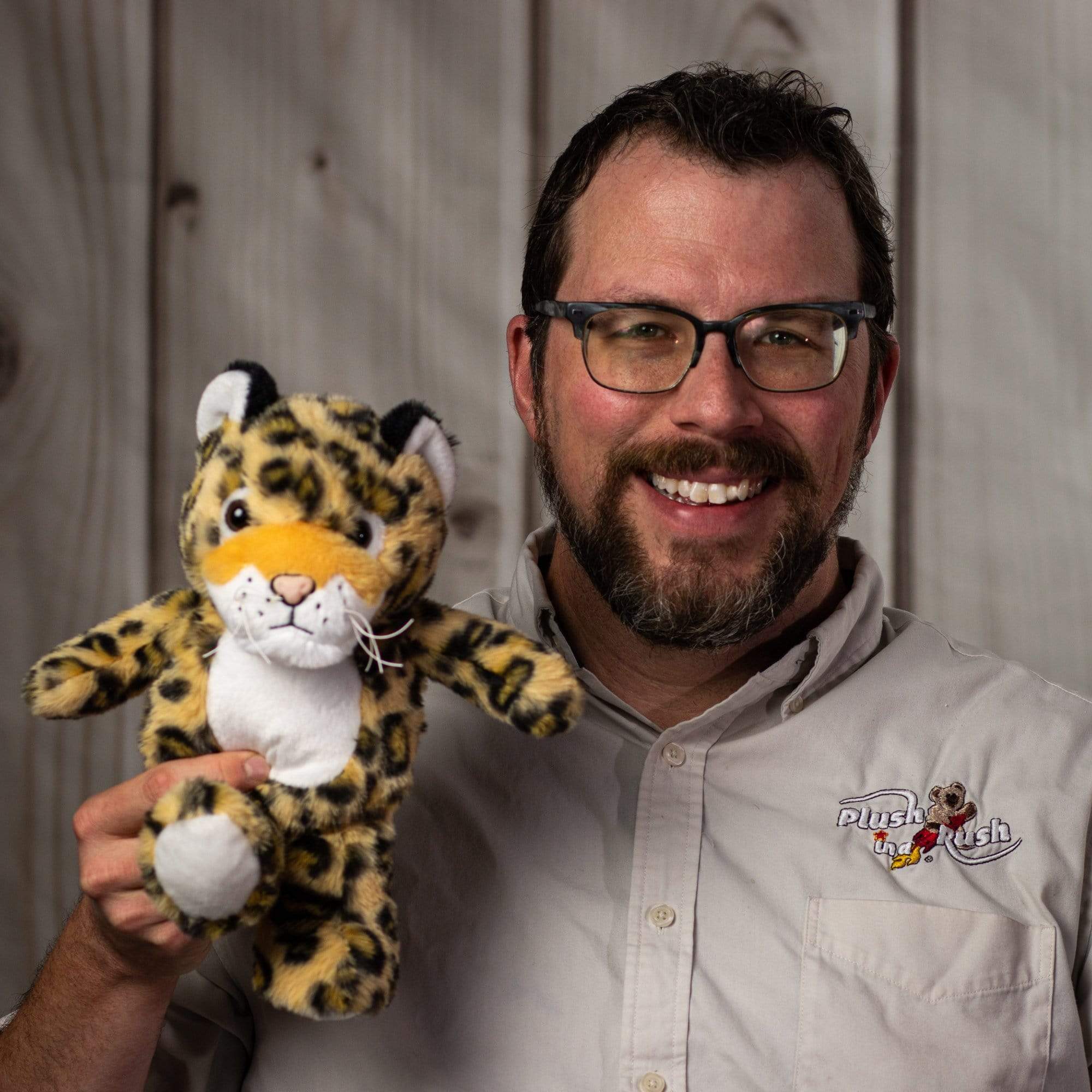 A man holds a spotted leopard that is 11 inches tall while standing