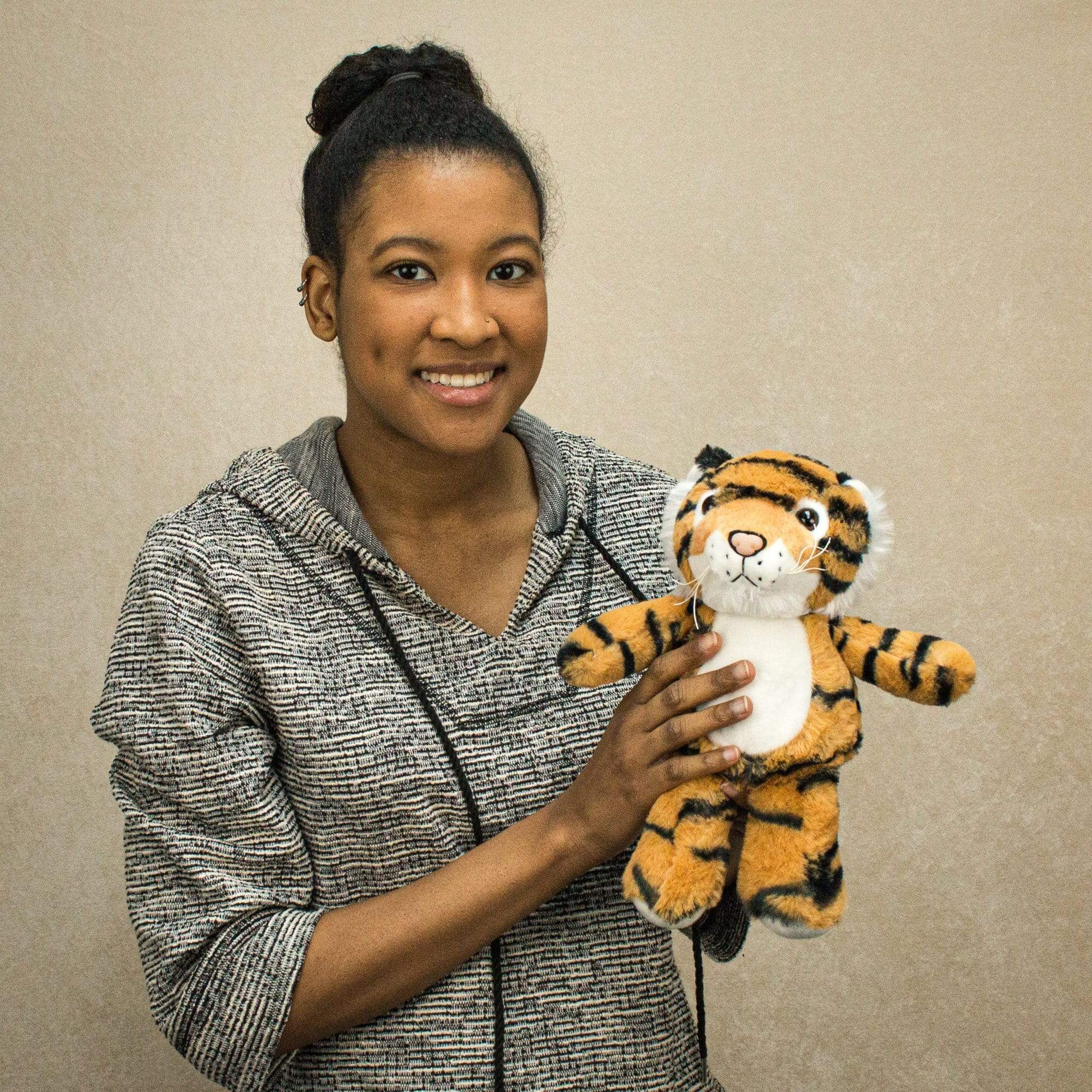 A woman holds a stripped tiger that is 11 inches tall while standing