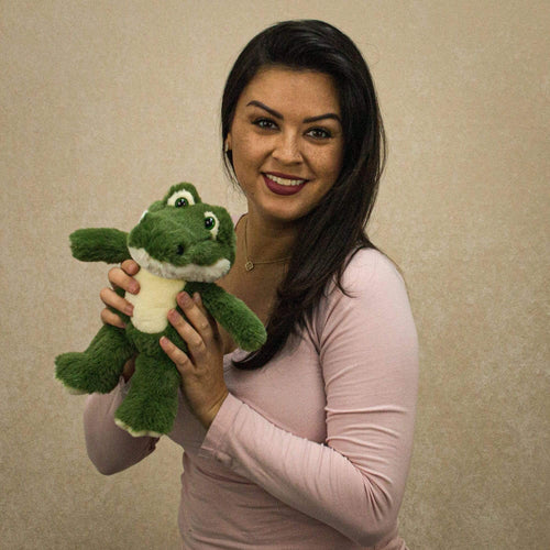 A woman holds a green alligator that is 11 inches tall while standing