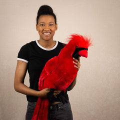 A woman holds a red cardinal bird that is 18 inches tall while sitting