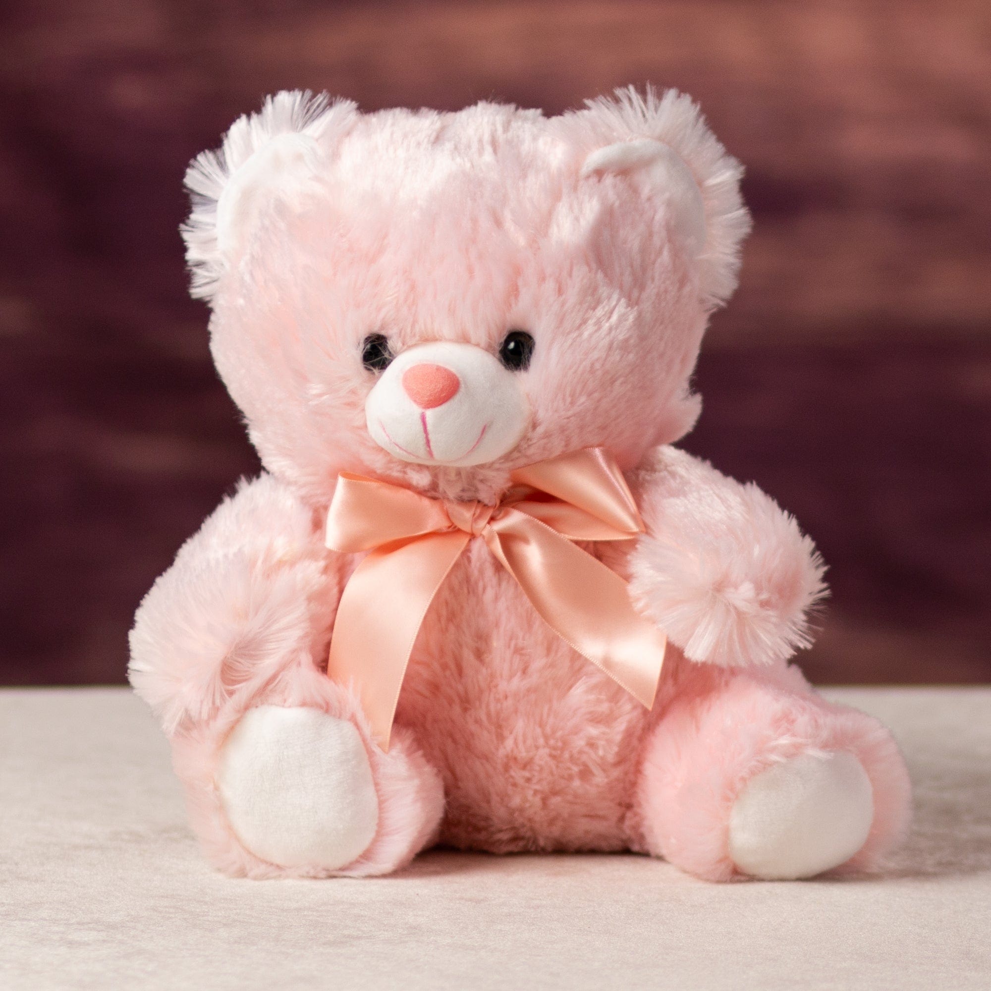 A pink bear that is 10 inches tall while sitting