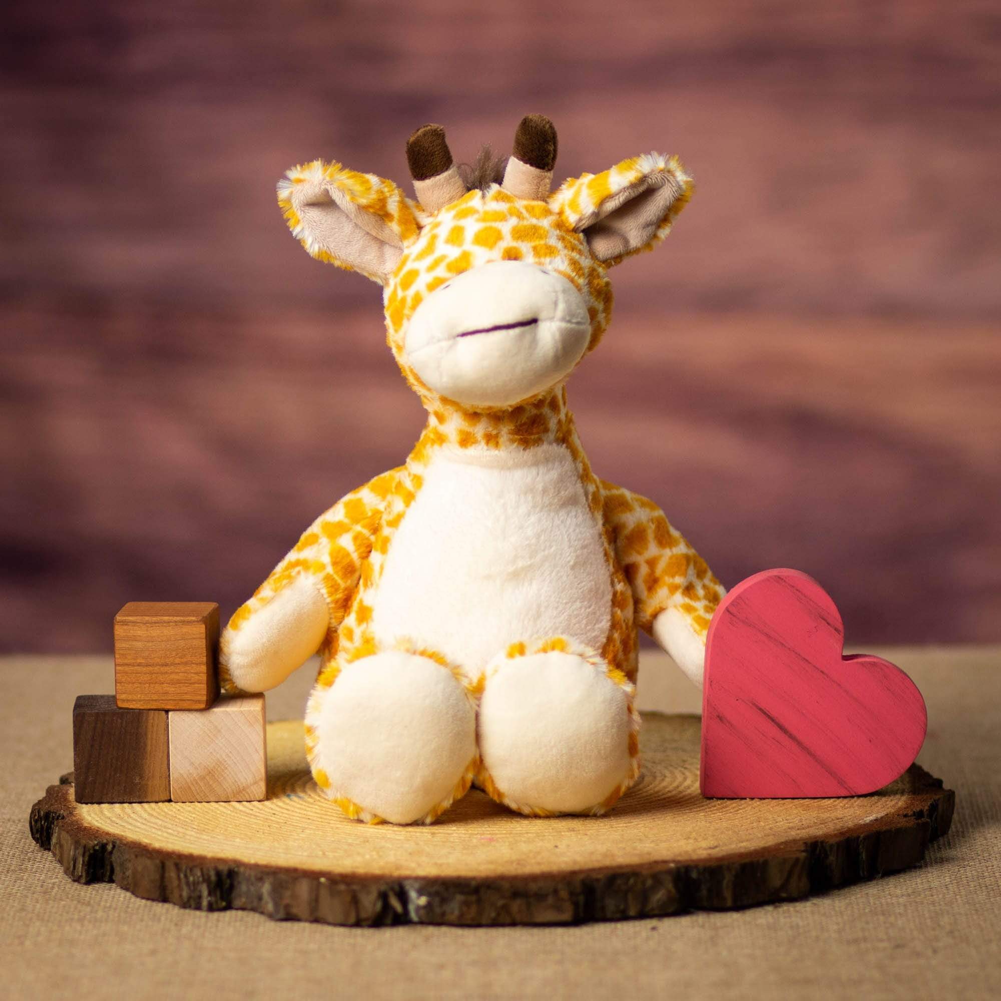 A giraffe that is 12 inches tall while standing in a sitting position on a piece of wood