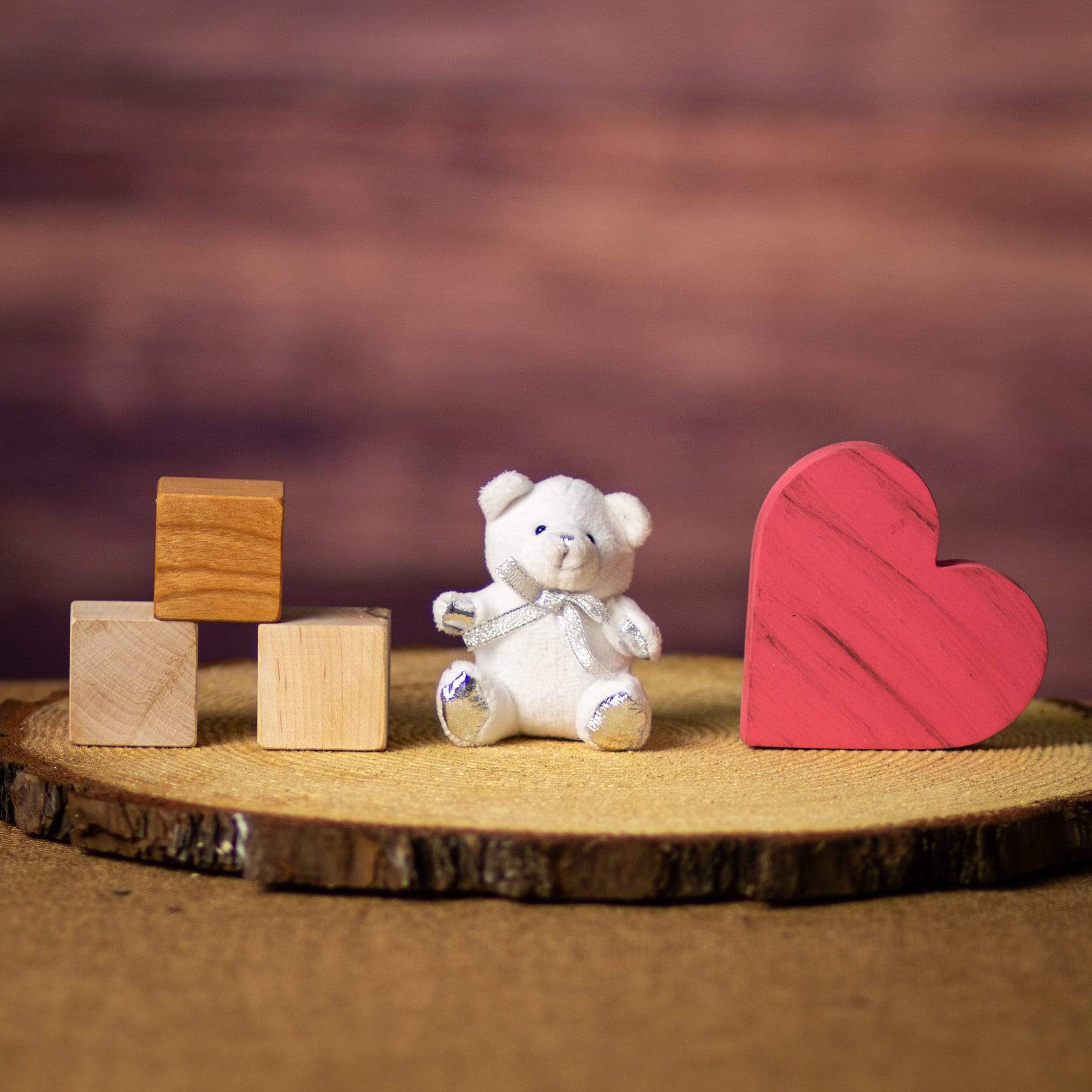 A white bear that is 3.5 inches tall while sitting with a silver bow and paws on top of a piece of wood