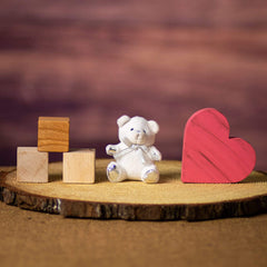 A white bear that is 3.5 inches tall while sitting with a silver bow and paws on top of a piece of wood