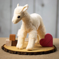 A beige llama that is 12 inches tall while standing on top of a piece of wood