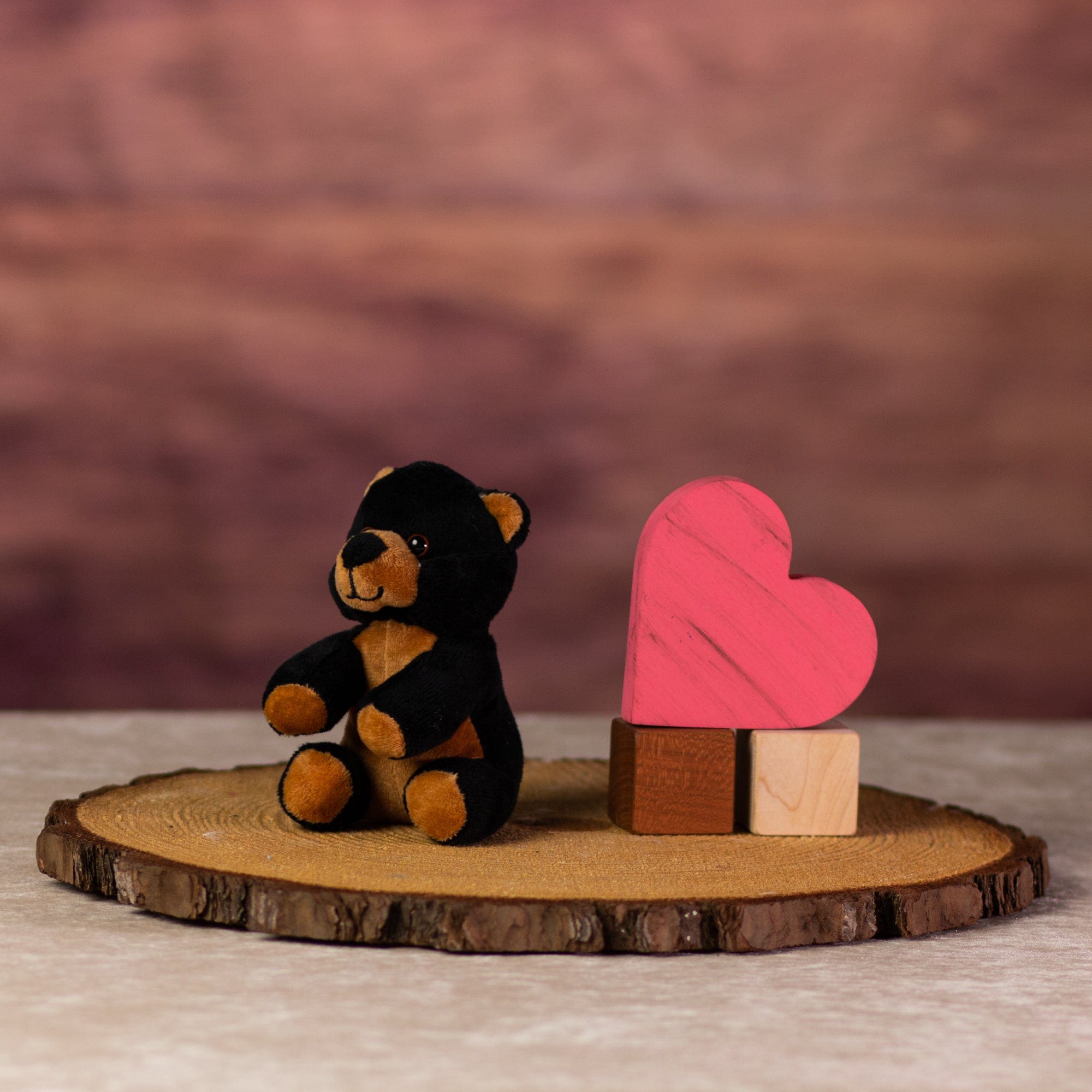 A black and brown bear that is 5 inches tall while sitting next to wooden blocks