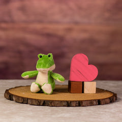 A green alligator that is 5 inches tall while sitting next to wooden blocks