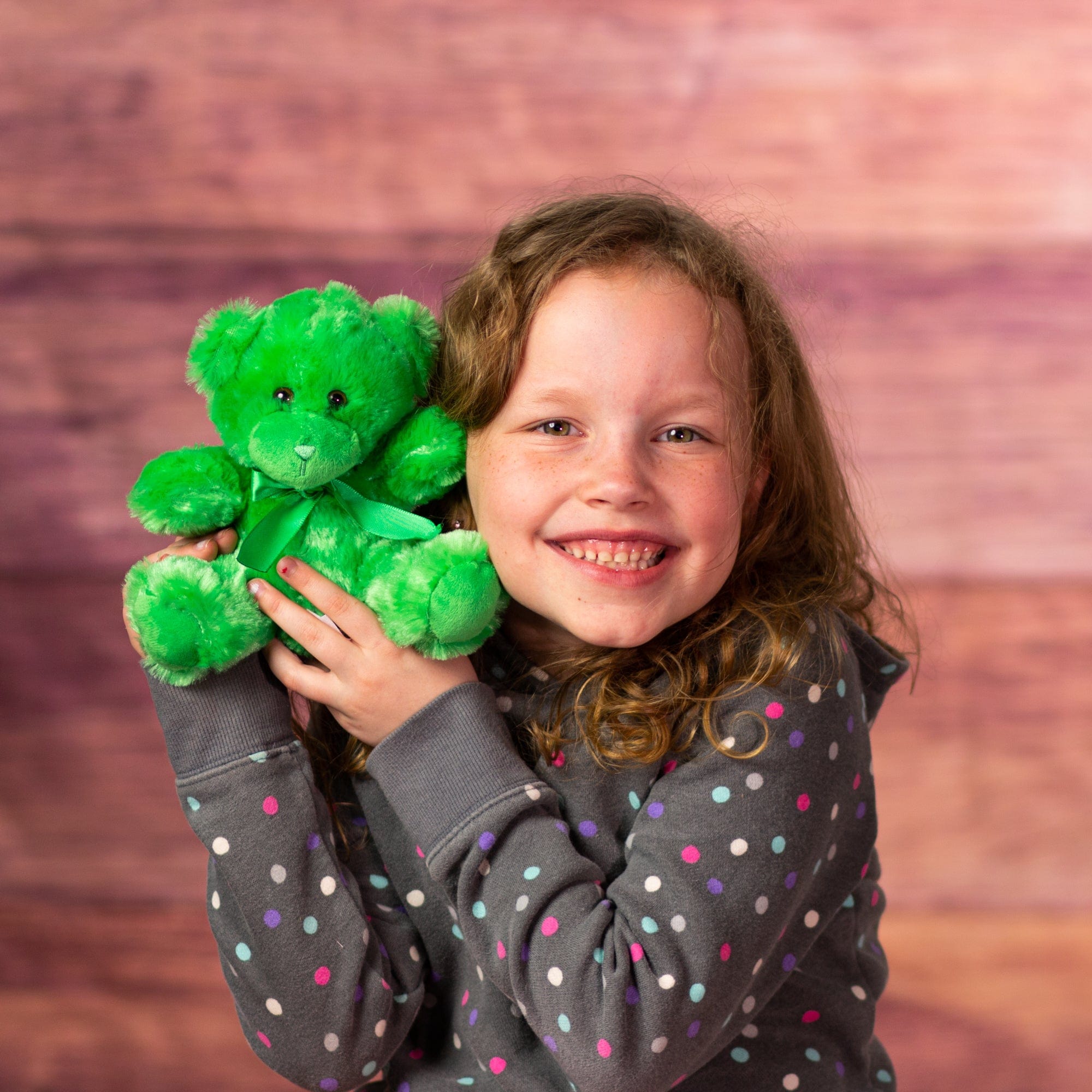 girl holding stuffed 6 in green bright and cheery bear with bow around her neck