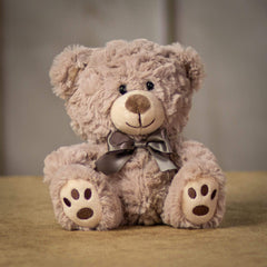 A beige bear that is 7 inches tall while sitting with paw prints on its feet