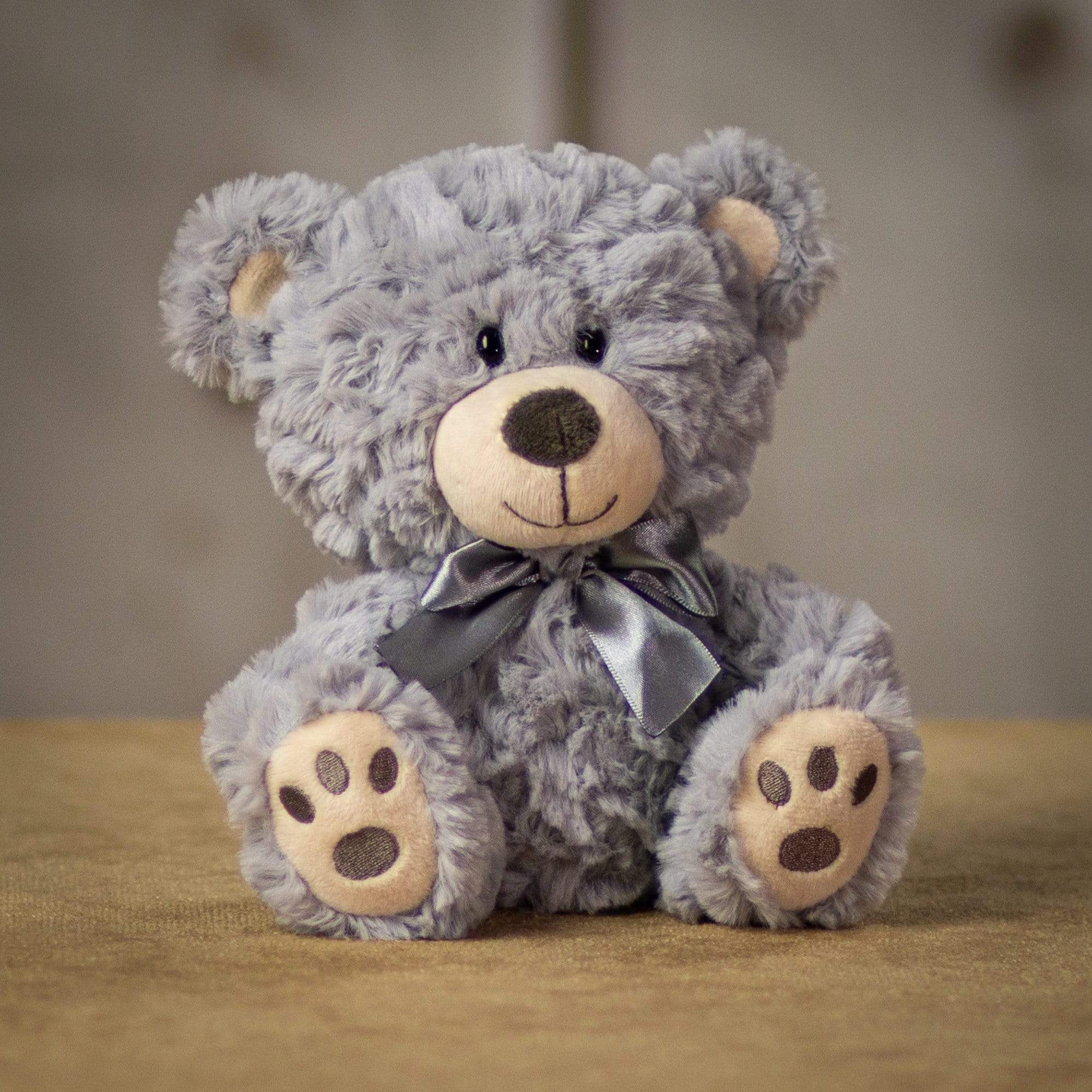 A gray bear that is 7 inches tall while sitting with paw prints on its feet