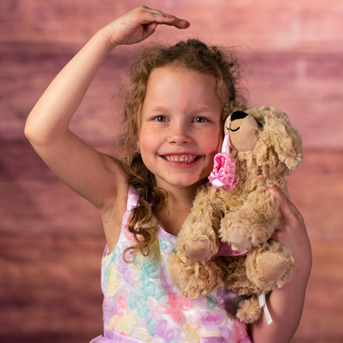 girl holding 10 in stuffed ballerina dog wearing a tutu and bows holding slippers