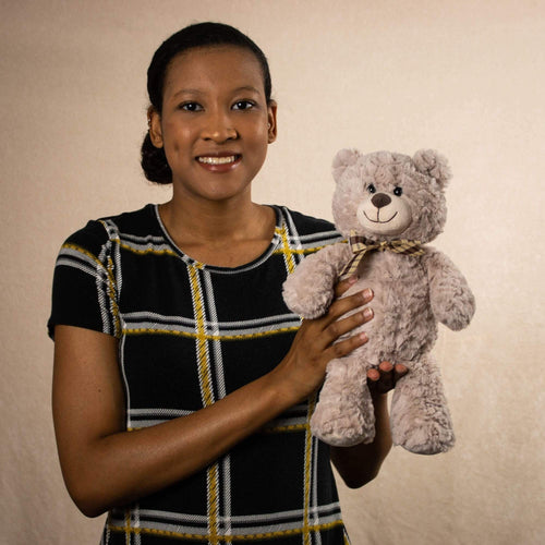 A woman holds a brown bear that is 13 inches tall while standing