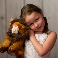 A little girl holding a brown lion that is 10 inches tall while standing