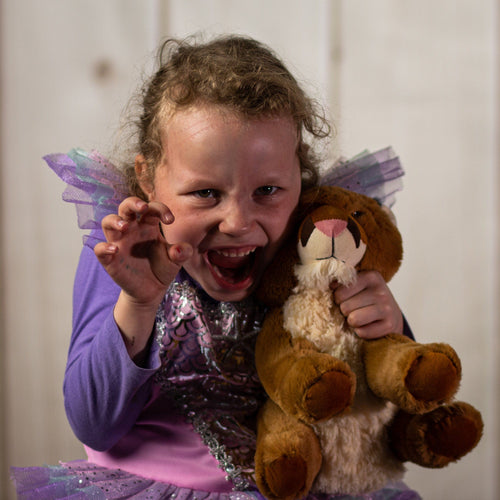 A little girl holding a brown cougar that is 10 inches tall while sitting