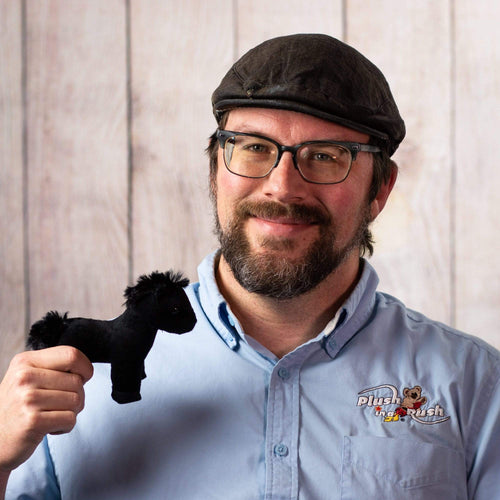 Man holds a small black horse stuffed animal