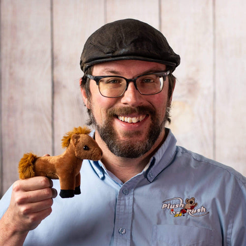 A man holds a small brown horse stuffed animal