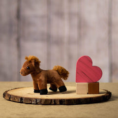 A small brown horse stuffed animal sitting on a log slice with props