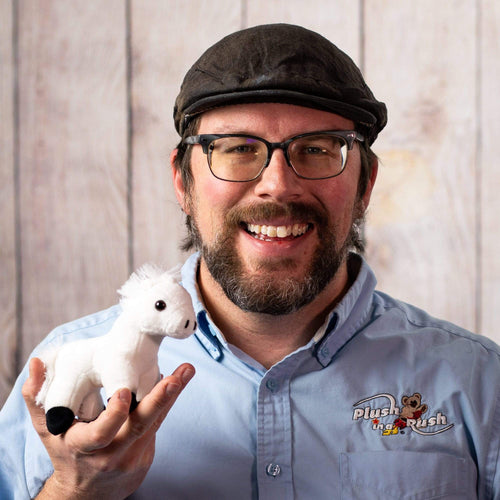 A man holds a small white horse stuffed animal