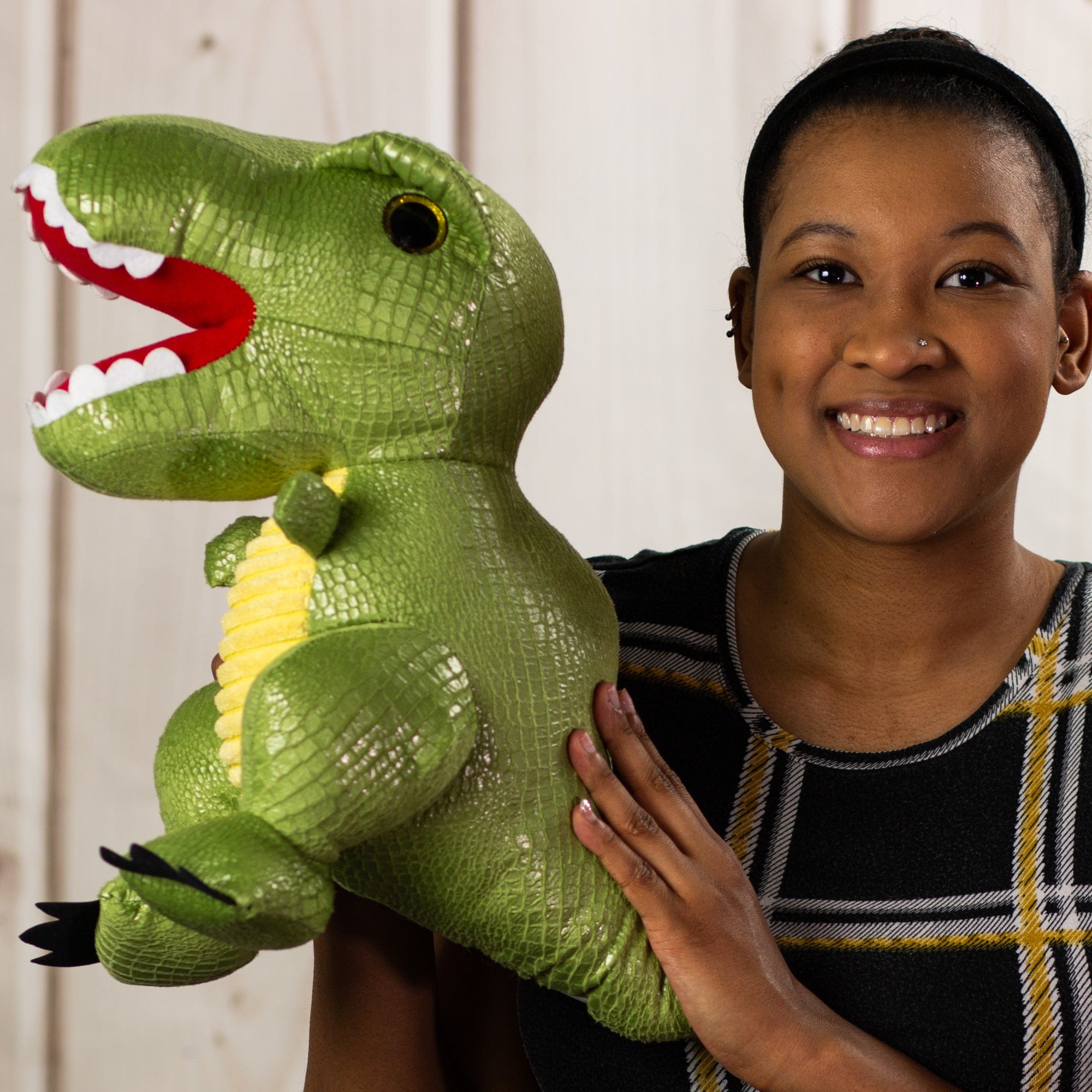 A woman holding a green dinosaur that is 14 inches tall while standing