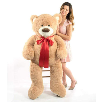 A woman next to a beige bear that is 60 inches tall while standing