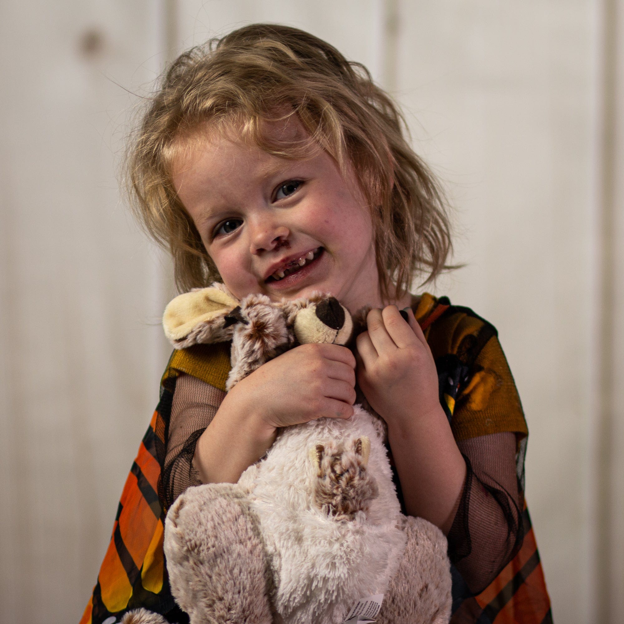 A little girl holding a beige kangaroo that is 14 inches tall while standing with a little joey inside