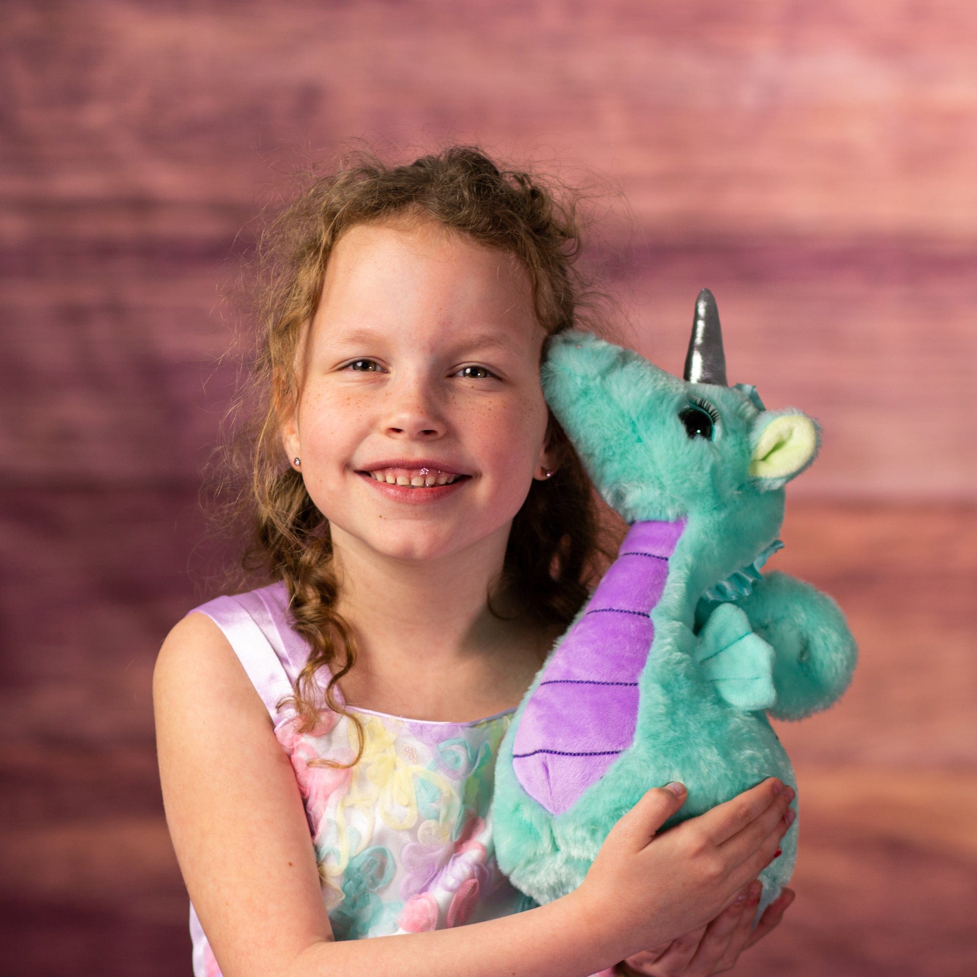 girl holding stuffed 11 in teal seahorse unicorn with eyelashes and silver horn