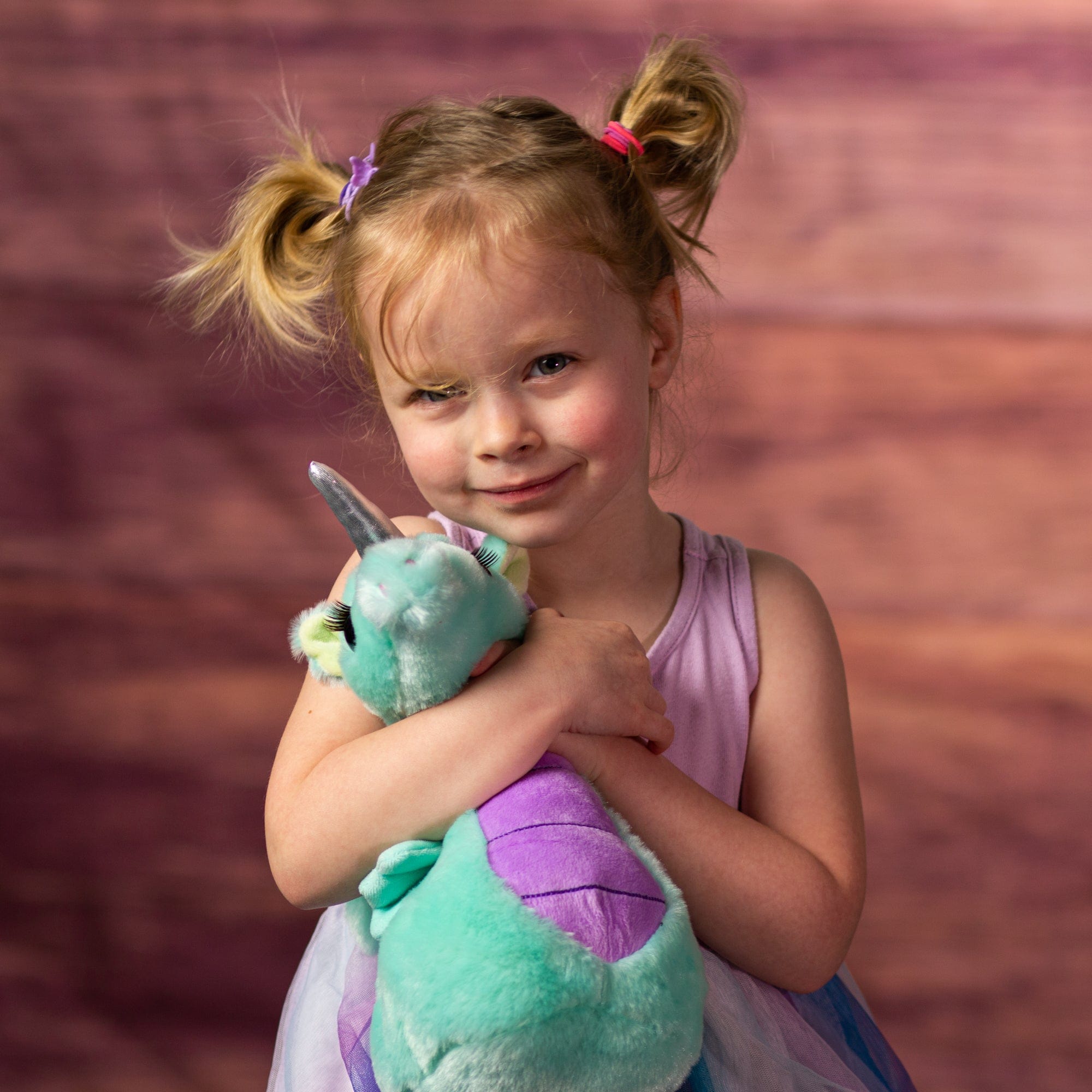 girl holding stuffed 11 in teal seahorse unicorn with eyelashes and silver horn