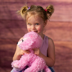 girl holding stuffed 10 in pink poodle with pink glitter eyes and eyelashes wearing a bow