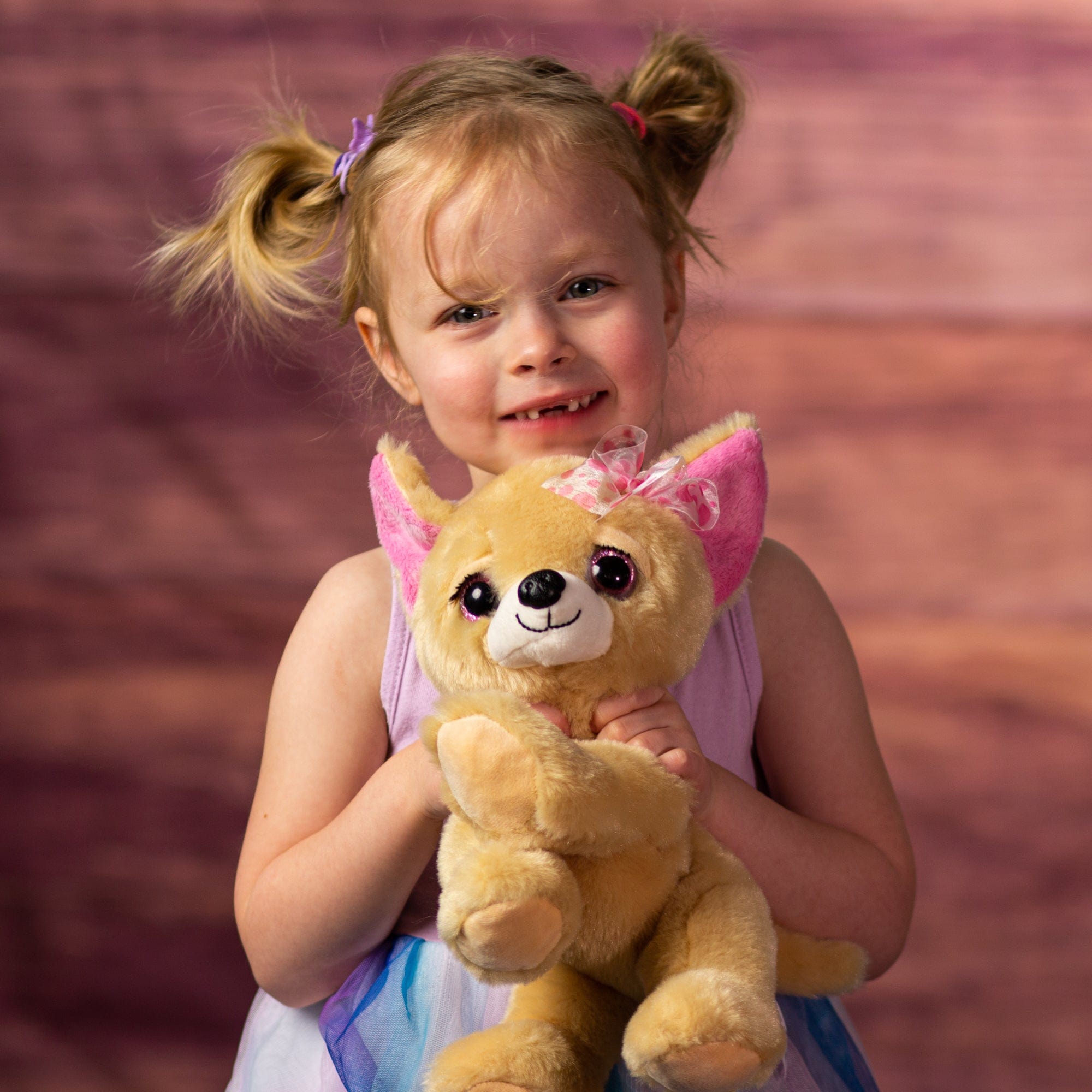 girl holding 10 in stuffed chihuahua with pink glitter eyes and eyelashes wearing a pink bow