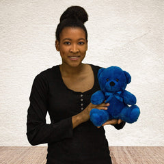 A woman holds a blue bear that is 9 inches tall while sitting