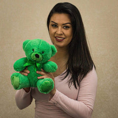 A woman holds a green bear that is 9 inches tall while sitting