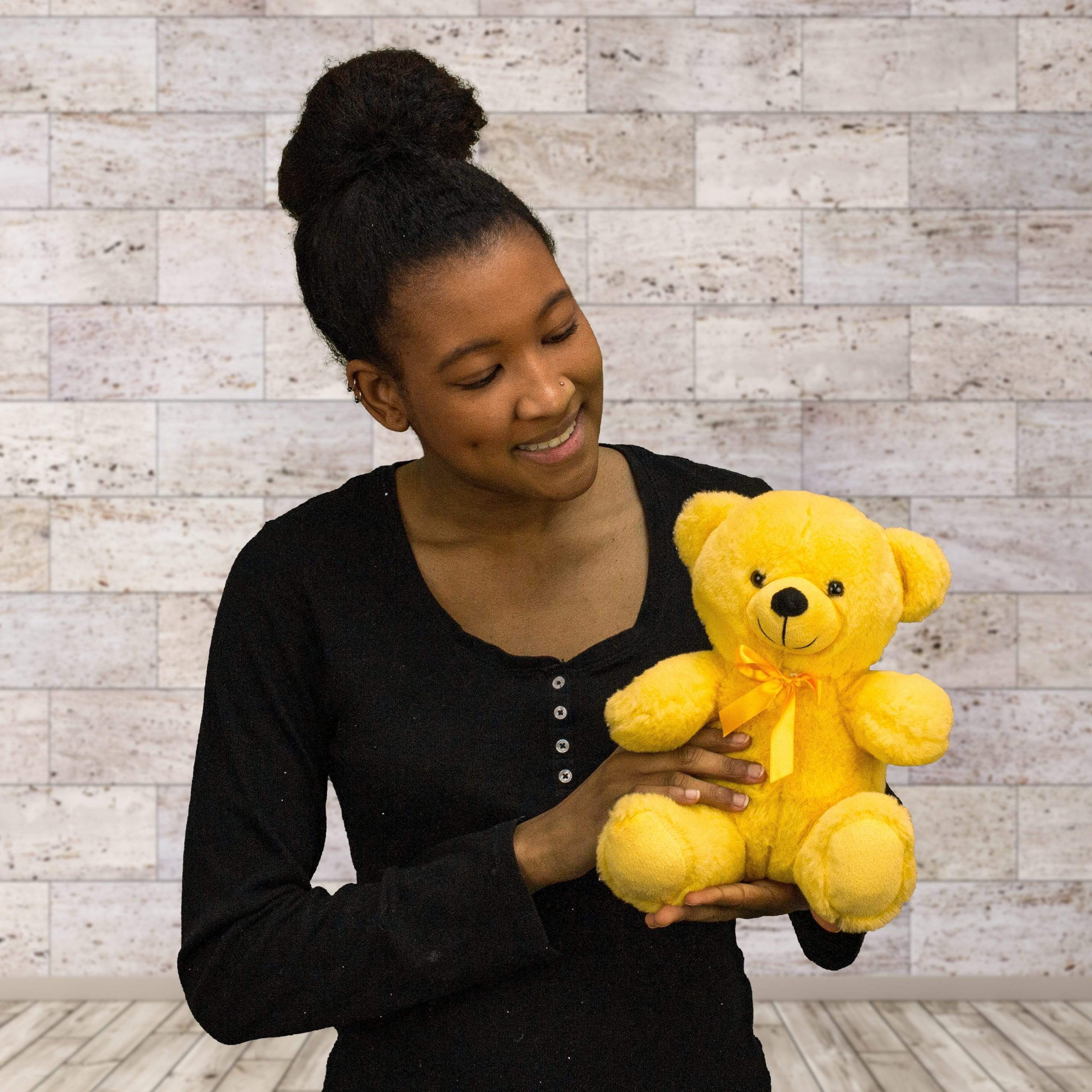 A woman holds a bright yellow bear that's 9 inches tall while sitting